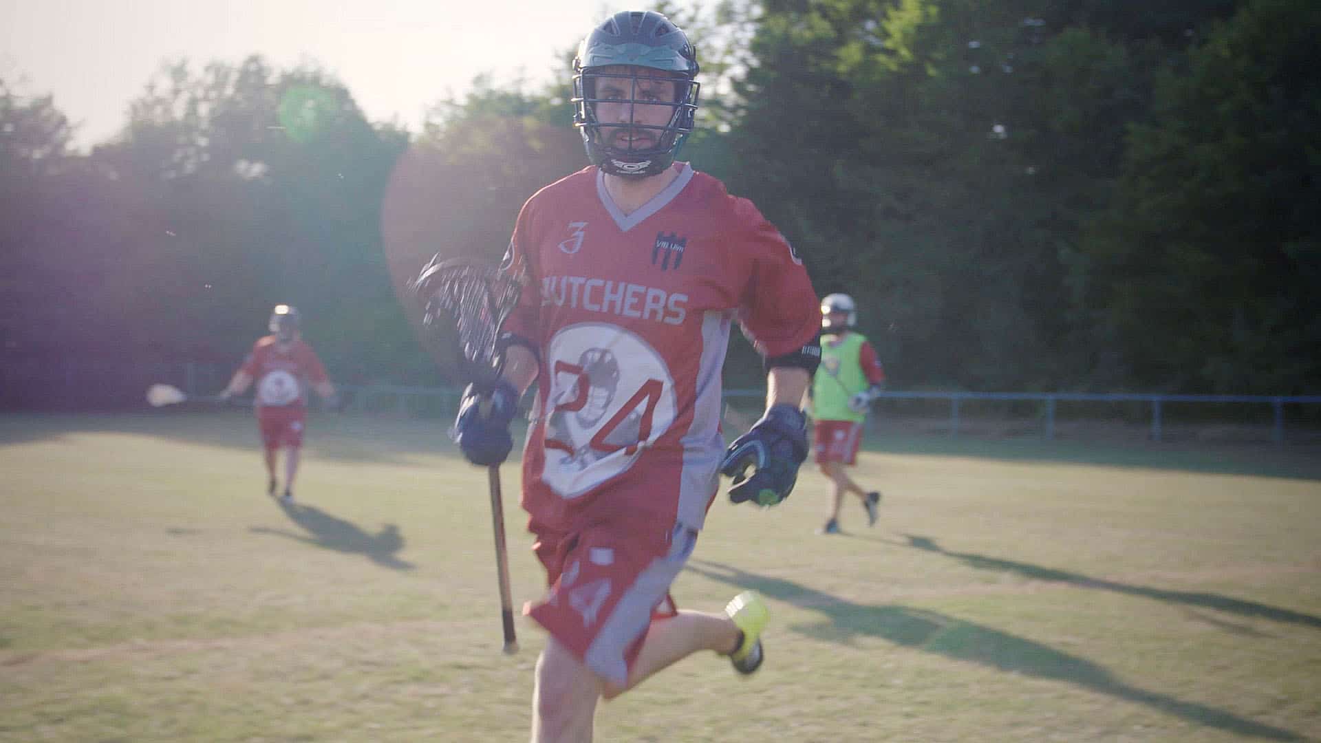 Drei Lacrosse Spieler spielen ehrgeizig auf dem Feld.